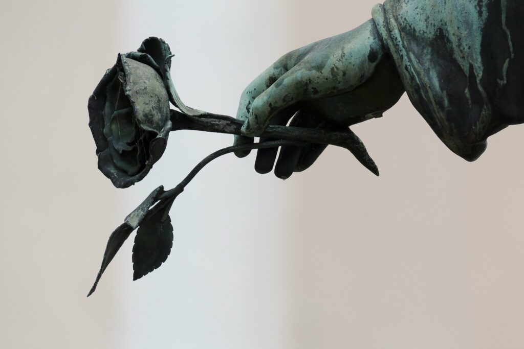 Hand einer Friedhofs-Skulptur mit Rose