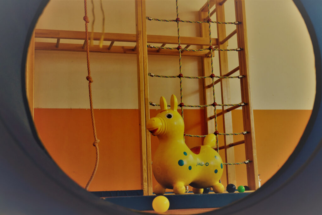Blick durch eine Krabbelröhre auf ein Hüpfpferdchen „Rody“ in der Turnhalle der Ev. Kindertagesstätte der Johanneskirchengemeinde