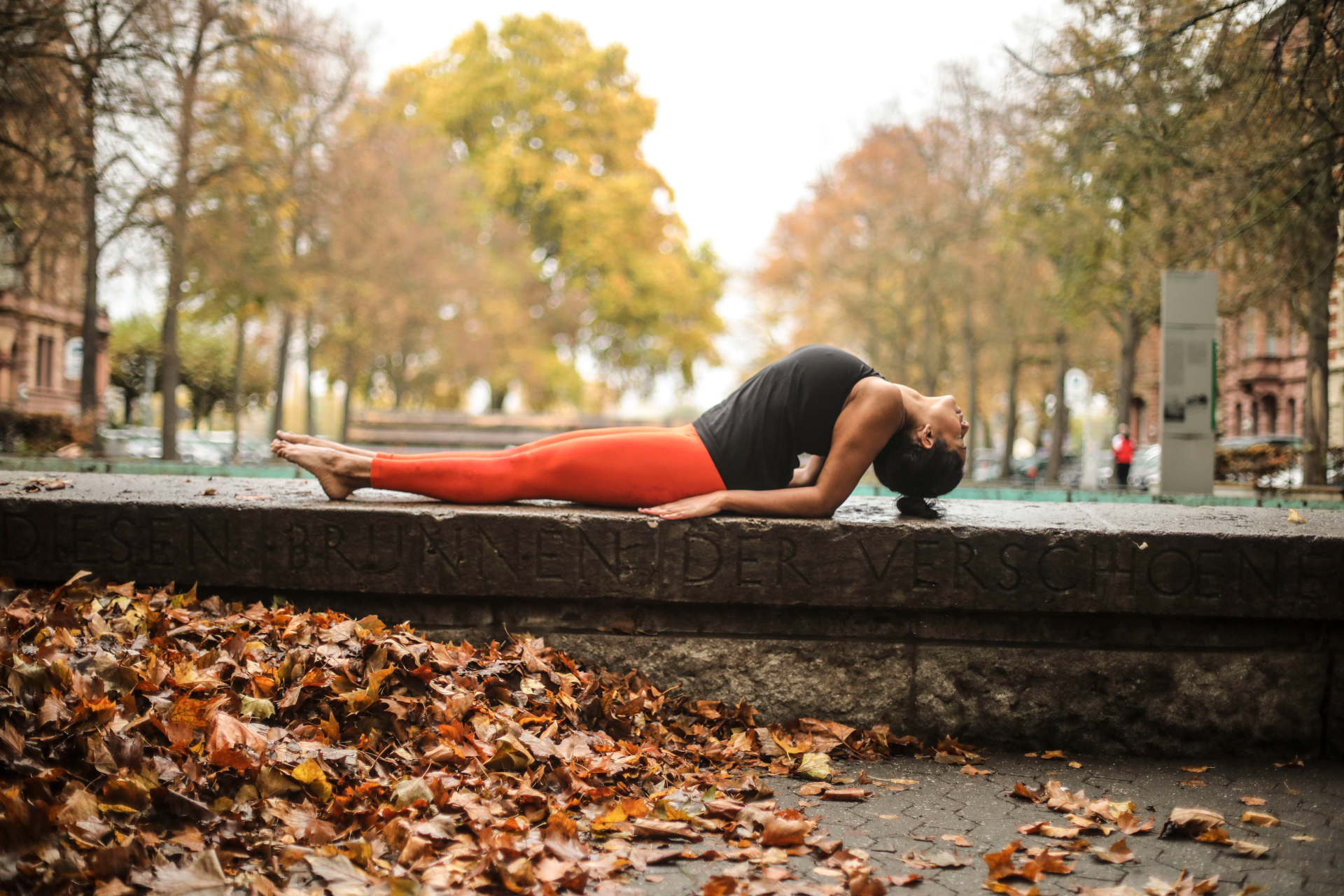 junge Frau macht Yoga-Übung am Rand eines Brunnens